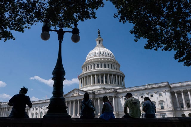 Visitors to the U.S. Capitol rest in the shade on Capitol Hill in Washington, D.C., U.S., June 25, 2025. REUTERS/Nathan Howard/File Photo