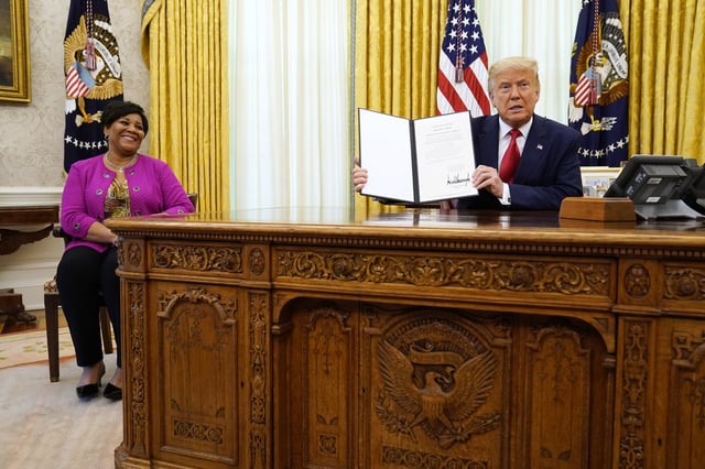 FILE - President Donald Trump holds up a full pardon for Alice Marie Johnson, left, in the Oval Office of the White House on Friday, Aug. 28, 2020. (AP Photo/Evan Vucci, File)