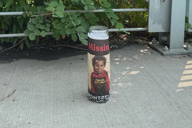 A lone candle bearing a photo of Montrell Williams stands near a cycling path in Garrison Park by the Bronx River.