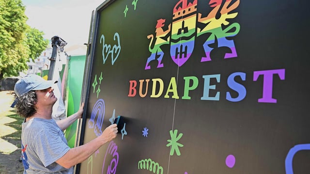 Ein Arbeiter bereitet ein Regenbogenplakat mit dem Logo des Budapester Rathauses in der Innenstadt der ungarischen Hauptstadt vor.