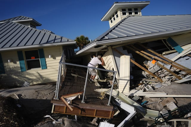 FILE - A property owner, who preferred not to give his name, peers into the remains of the second floor unit where he lived with his wife while renting out the other units, on Manasota Key, in Englewood, Fla., following the passage of Hurricane Milton, Oct. 13, 2024. (AP Photo/Rebecca Blackwell, File)