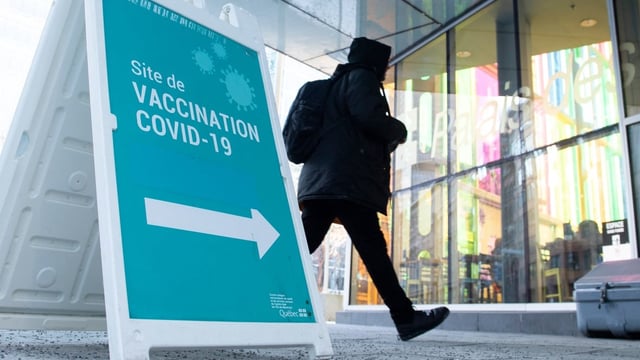 A man walks by a COVID-19 vaccination sign in Montreal on Dec. 23, 2021. According to an expert group charged by the World Health Organization to investigate how the COVID-19 pandemic started, scientists still aren't completely sure of the origins.