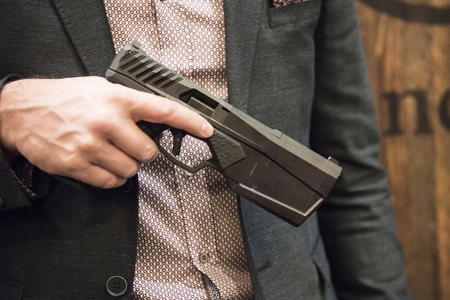 FILE - Josh Waldron, co-founder and CEO of SilencerCo, holds a 9mm handgun with a suppressor embedded into the barrel, Jan. 17, 2017, in Las Vegas. (AP Photo/Lisa Marie Pane, File)