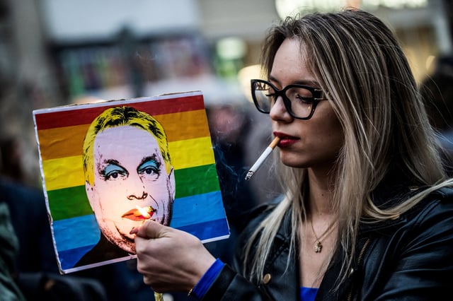 Une femme allume une cigarette placée dans un panneau représentant le Premier ministre hongrois Viktor Orban, lors d’une manifestation, après que le parlement hongrois a adopté une loi interdisant aux communautés LGBTQ+ de tenir la marche annuelle des fiertés et permettant une contrainte plus large sur la liberté de réunion, à Budapest, Hongrie, le 25 mars 2025.