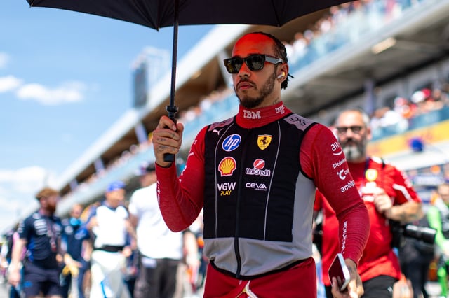 Lewis Hamilton of Great Britain and Ferrari seeks shade under an umbrella in the pit lane during the F1 Grand Prix of Canada at Circuit Gilles-Villeneuve on June 15, 2025 in Montreal, Canada.
