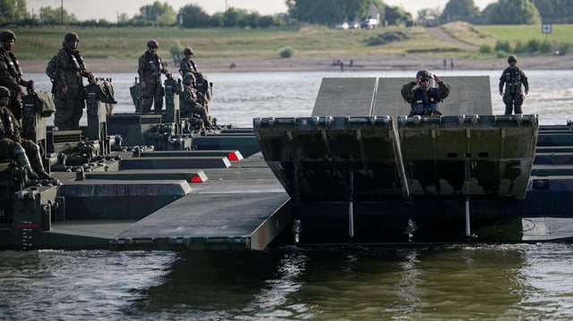 Eine aus Amphibienfahrzeugen gebildete Fähre transportiert Fahrzeuge im Rahmen der ganztägige Militärübung zur Überquerung des Rheins.