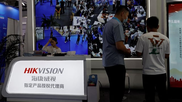 A staff member sits in front of a screen displaying footage from surveillance cameras at the Hikvision booth at Security China, an exhibition on public safety and security, in Beijing on June 7, 2023.