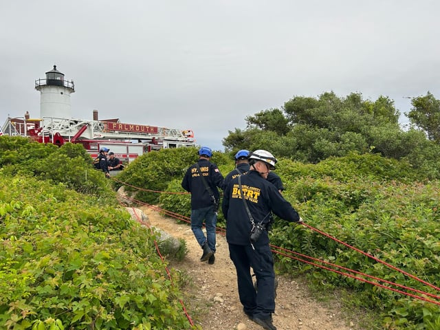 A rescue crew helping to carry a person to safety after they were injured on a steep trail in Falmouth, Massachusetts, near the Nobska Lighthouse on Saturday, June 28, 2025.
