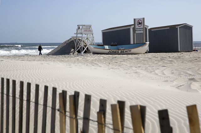 FILE - A person walks by the water at Jones Beach in Wantagh, N.Y., May 21, 2020. (AP Photo/Kathy Willens, File)