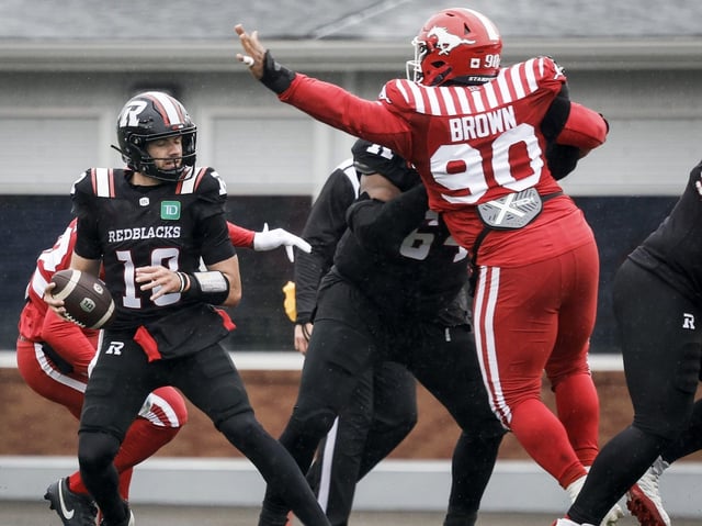 Ottawa Redblacks quarterback Dustin Crum, left, looks for a receiver as Calgary Stampeders' Miles Brown tries to block his pass during second half CFL football action in Calgary, Saturday, June 21, 
