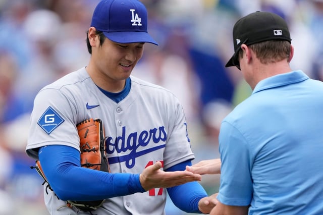 Dodgers starting pitcher Shohei Ohtani is checked by third base umpire Alex Tosi after pitching in the first inning of a baseball game against the Kansas City Royals, Saturday, June 28, 2025, in Kansas City, Mo. (AP Photo/Charlie Riedel)
