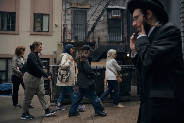 Tour participants walk past an ultra-Orthodox Jewish man during a tour by Frieda Vizel of the Hasidic section of Williamsburg in the Brooklyn borough of New York on Monday, June 16, 2025. (AP Photo/Andres Kudacki)