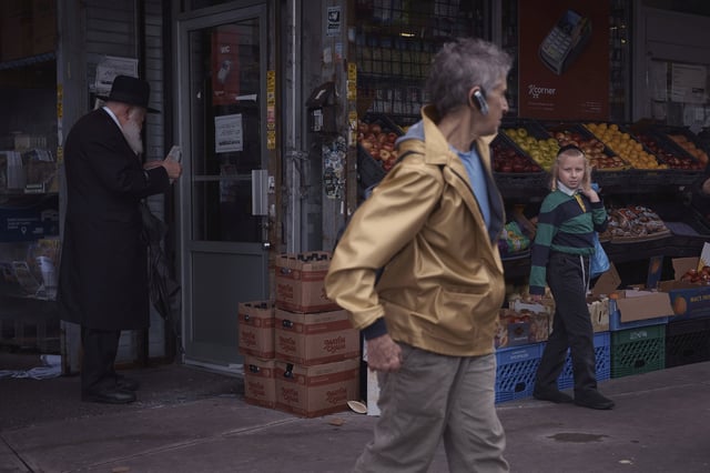 A tourist passes ultra-Orthodox Jews during a guided walk through the Hasidic section of Williamsburg in the Brooklyn borough of New York on Monday, June 16, 2025. (AP Photo/Andres Kudacki)
