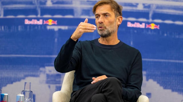 Jürgen Klopp sitzt auf einem Podium und spricht.