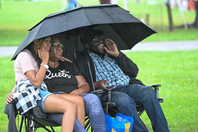 Sept. 28, 2024: Under the shelter from the drizzling rain, Zionah Hill, Samiyyah Hill and Hustace Wade listen to the band Midnite Run during the Taneytown Harvest Festival. (Karen Jackson/Freelance)