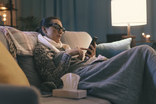 A stock image showing a sick person using a smartphone.