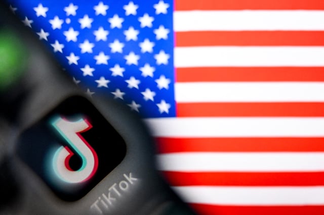 A photo taken on April 10, 2025 shows the Chinese social networking service TikTok&#39;s logo on a smartphone screen (L) and US&#39; flag illustration on a laptop screen in Frankfurt am Main, western Germany.