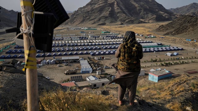 A Taliban fighter on a hill overlooking a camp housing Afghan refugees in Torkham