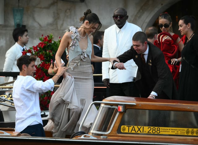 Italian model Vittoria Ceretti (C), British fashion editor Edward Enninful and Indian philanthropist Natasha Poonawalla (2ndR) leave the Gritti Palace Hotel ahead of the wedding of Amazon's founder Jeff Bezos with Lauren Sanchez in Venice on June 26, 2026. Celebrities in superyachts sail into Venice this week for the three-day wedding party of Amazon tycoon Jeff Bezos and Lauren Sanchez, despite irate locals who say the UNESCO city is no billionaire's playground. The tech magnate and journalist have reportedly invited about 200 guests to their multi-million dollar nuptials in the Italian city, which are expected to kick off on June 26 and end Saturday with a ceremony at a secret location.
