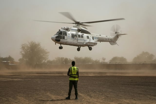 Un membre du Service aérien humanitaire des Nations unies (UNHAS) observe l'atterrissage d'un hélicoptère UNHAS à Dori, au Burkina Faso, le 31 mai 2024