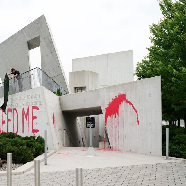 Workers spread a tarp to cover the words 'FEED ME' on the National Holocaust Monument in Ottawa, June 9.