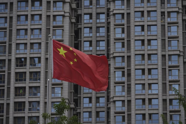 A Chinese national flag flutters against the residential building in Beijing, Monday, June 16, 2025. (AP Photo/Andy Wong)