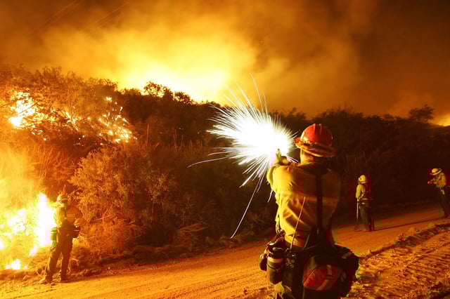A U.S. Forest Service firefighter fires flares into the brush to set a backfire in this archive photo from October 2005, which was taken near Calimesa, in Riverside County, California.