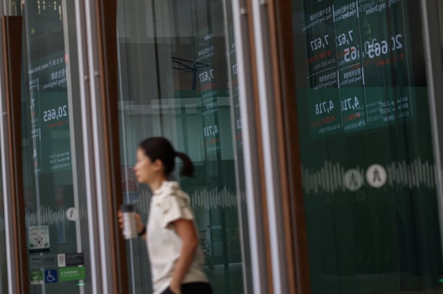 A screen reflecting on glass displays the Hang Seng stock index at the Central district in Hong Kong, China, April 7, 2025. REUTERS/Tyrone Siu