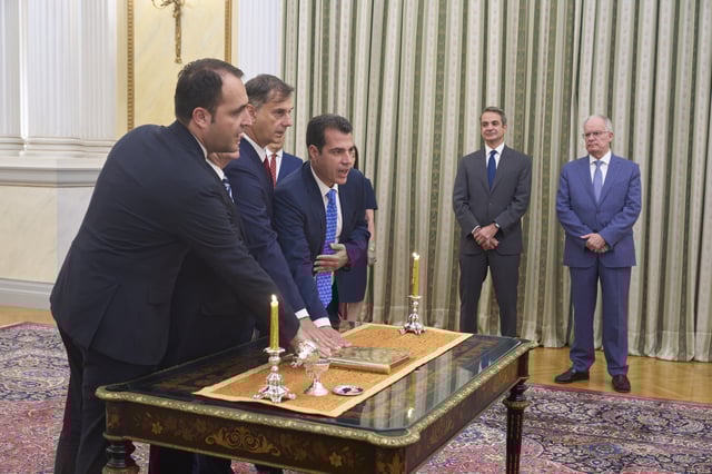 Members of Greece's new government take the oath during a swearing in ceremony in front of Greece's Prime Minister Kyriakos Mitsotakis, second right, and Greek President Konstantinos Tasoulas, right, at the Presidential palace, in Athens, on Monday, June 30, 2025. (AP Photo/Petros Giannakouris)