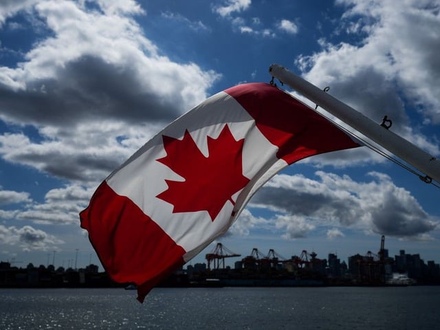 A Canadian flag flies on a boat with the downtown Vancouver skyline in the background.