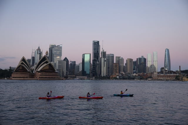 Kayakers paddle past the Sydney Opera House and Central Business District (CBD) skyline at sunrise in Sydney, Australia, April 29, 2025. REUTERS/Hollie Adams