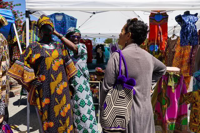Debo Fashokun, left, of Rema Collections, helps customer Dr. Eva Silot Bravo as she shops at the Berkeley Flea Market on April 30, 2022. The market has closed after 50 years, citing financial losses and uncertain plans to relocate amid housing development near the Ashby BART station.