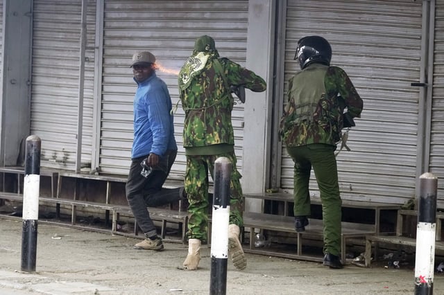ADDS NAME: EDS NOTE: GRAPHIC CONTENT - A Kenyan policeman, center, shoots vendor Boniface Kariuki, left, during a protest in Nairobi, Kenya, Tuesday, June 17, 2025. (AP Photo/Brian Inganga)