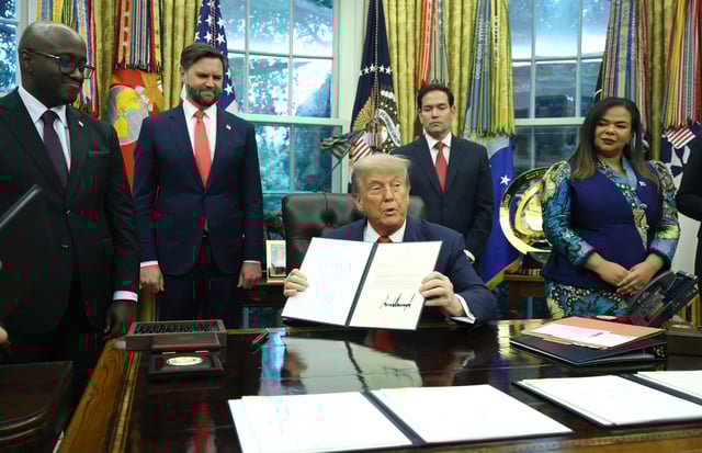 U.S. President Donald Trump sigs a letter of congratulations as he meets with Minister of Foreign Affairs and Cooperation of Rwanda Olivier Nduhungirehe and the Foreign Minister of the Democratic Republic of the Congo Thérèse Kayikwamba Wagner in the Oval Office at the White House on June 27, 2025.