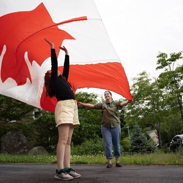 Kate Warman, 11, stands under a Canada flag that once flew over the Peace Tower while her mom Kristine and dad Casey (not pictured) unfurl the flag at their home in Halifax.