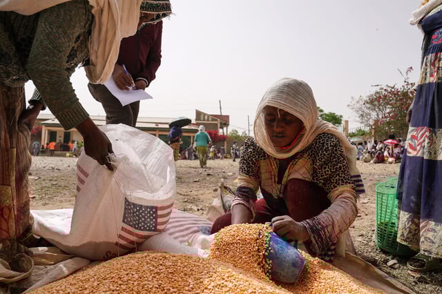 An aid worker distributes measured portions of yellow lentils supplied by USAID in Mekele, Ethiopia in 2021.