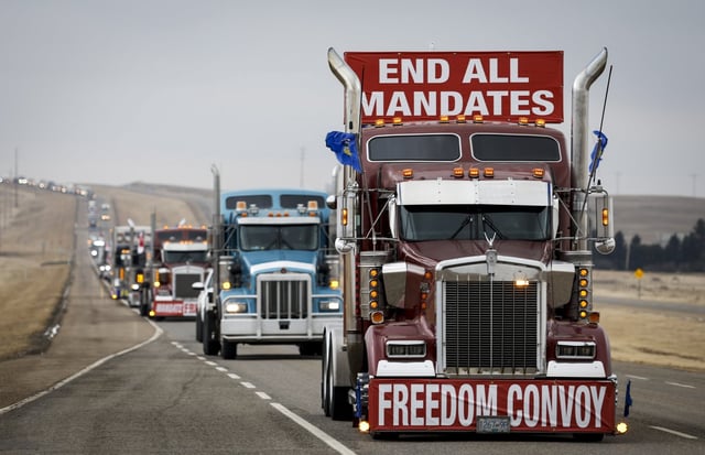 Anti-COVID-19 vaccine mandate demonstrators leave in a truck convoy after blocking the highway at the busy U.S. border crossing in Coutts, Alta., Tuesday, Feb. 15, 2022.THE CANADIAN PRESS/Jeff McIntosh