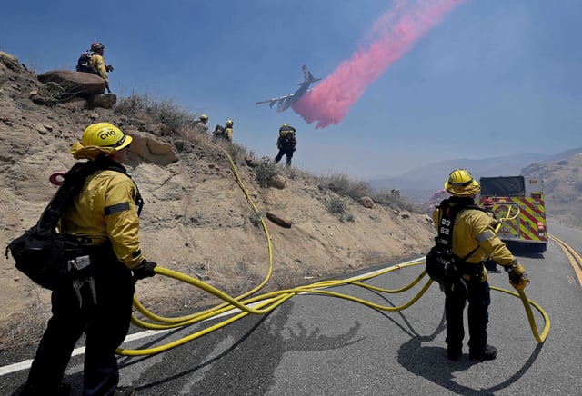 Banning, CA – June 30: Firefighters pull hose lines along Highway 243, also known as the Esperanza Firefighters Memorial Highway, as a plane drops fire retardant near Banning during the Wolf Fire on Monday, June 30, 2025. As of 2 p.m. the fire had burned 1,400 acres and was 30 percent contained following a heavy aerial attack. (Photo by Will Lester/Inland Valley Daily Bulletin via Getty Images)