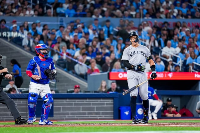 New York Yankees&#39; Aaron Judge, right, reacts after striking out against the Toronto Blue Jays during fourth-inning baseball game action in Toronto, Monday, June 30, 2025. (Thomas Skrlj/The Canadian Press via AP)