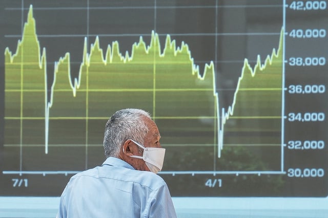A person looks at an electronic stock board showing Japan's Nikkei index at a securities firm Tuesday, July 1, 2025, in Tokyo. (AP Photo/Eugene Hoshiko)