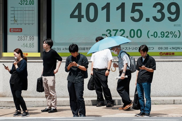 People stand in front of an electronic stock board showing Japan's Nikkei index at a securities firm Tuesday, July 1, 2025, in Tokyo. (AP Photo/Eugene Hoshiko)