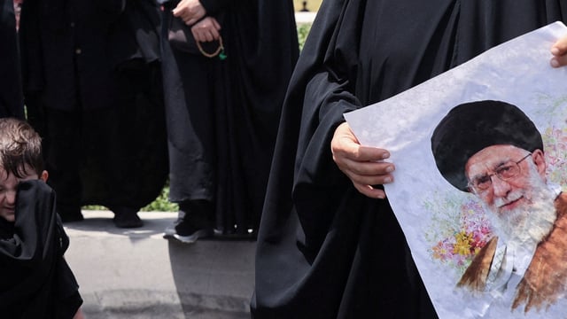 A woman holds a picture of Iran's Supreme Leader Ayatollah Ali Khamenei.