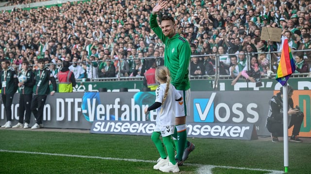 Christian Groß hält ein kleines Mädchen an der Hand und läuft ins Weser-Stadion ein. 