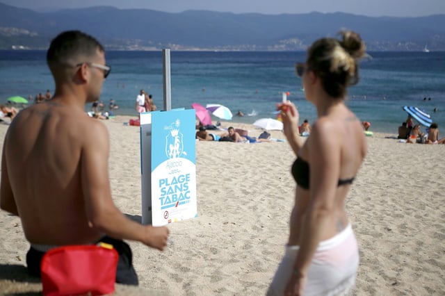 A man and woman smoke cigarettes by a non-smoking beach in Ajaccio, on the French Mediterranean island of Corsica.