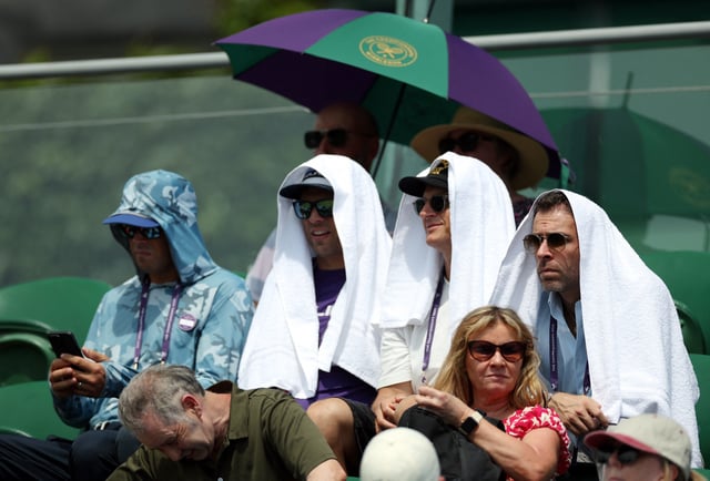 Tennis - Wimbledon - All England Lawn Tennis and Croquet Club, London, Britain - July 1, 2025 Spectators in the stands of court three use towels for cover amid the heatwave during the first round match between Tommy Paul of the U.S. and Britain's Johannus Monday REUTERS/Isabel Infantes