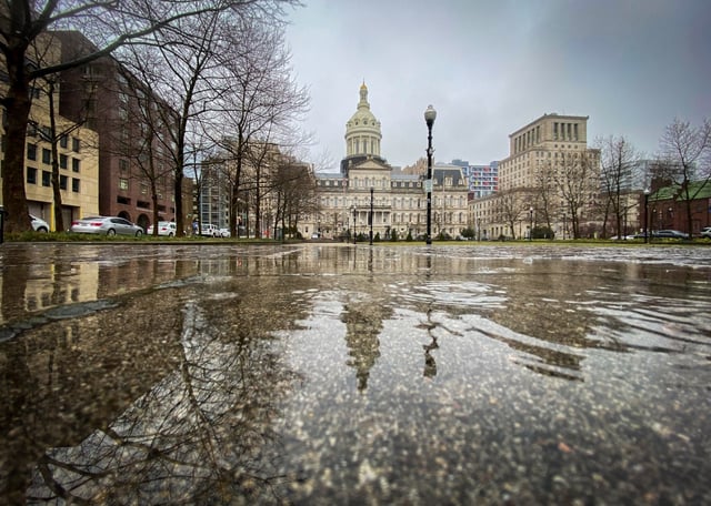 Baltimore City Hall is reflected in a puddle as rain falls Thursday morning, setting the tone for a wet day ahead.