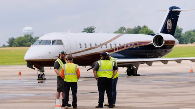 Workers are pictured in front of a jet at the Youngstown - Warren Regional Airport in Vienna, Ohio, Monday, June 30, 2025, where a day earlier a plane crashed on take off killing all onboard. 