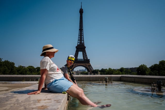 Tourists cool off in the Trocadero Fountain, in front of the Eiffel Tower in Paris, on July 1, 2025, as temperatures in France are expected to hit a peak today, according to the Meteo France weather agency, with some areas expected to soar beyond 40 degrees Celsius (104 degrees Fahrenheit). Paris braced for blistering temperatures, with the French capital on red alert as an early summer heatwave spread into parts of northern Europe less accustomed to such extremes. Scientists say human-induced climate change is making such heatwave events more intense, frequent and widespread. (Photo by Dimitar DILKOFF / AFP) (Photo by DIMITAR DILKOFF/AFP via Getty Images)