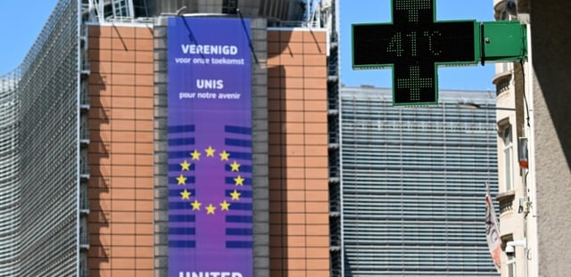 Un thermomètre de pharmacie affiche 41°C, avec en arrière-plan le siège de la Commission européenne, à Bruxelles, le 23 juin 2025