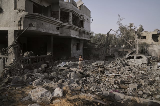 A Palestinian girl stands atop the rubble of the Al-Aimawi family's home that was destroyed by Israeli airstrikes in Al-Zawaideh, Gaza Strip, Tuesday, July 1, 2025. (AP Photo/Abdel Kareem Hana)